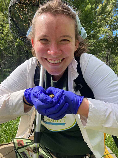 woman grinning and holding a tiny frog