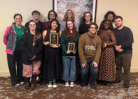 group of people posing together, holding award plaques.