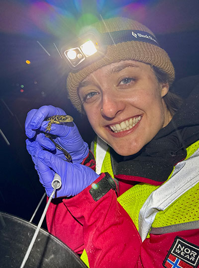 woman at night wearing a headlamp and holding a frog