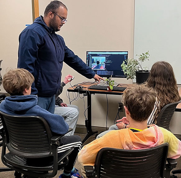 three children and an adult at a computer