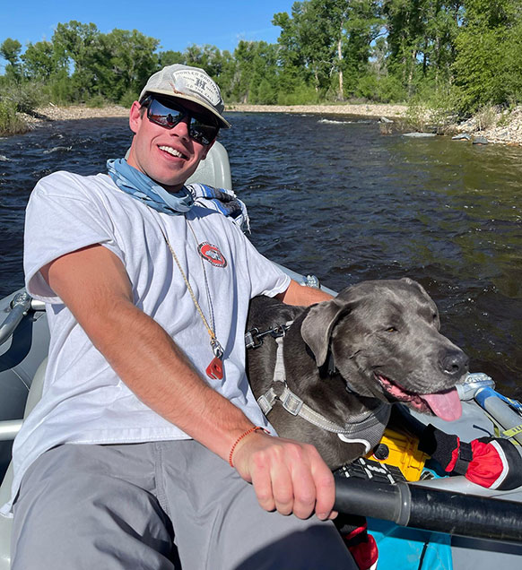 man and a dog on a river in a boat