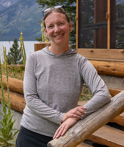 woman leaning against a rustic wood railing outside