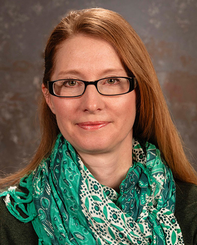 A woman stands in front of gray background