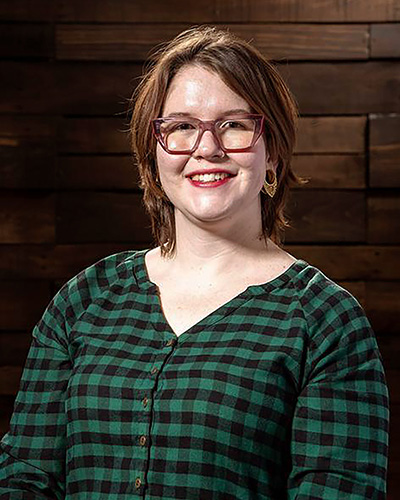 A woman stands in front of a wooden background