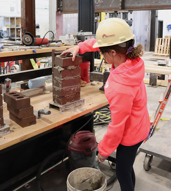 student works with bricks and mortar at a workbench