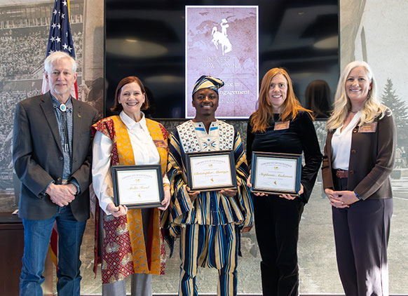 five people posing together with the middle two holding awards