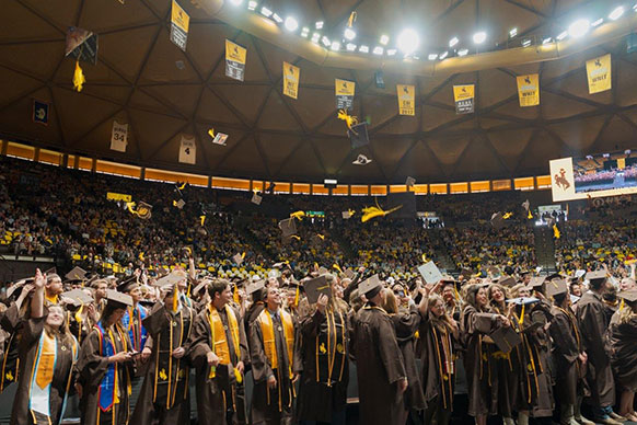 large space full of people in brown and gold caps and gowns