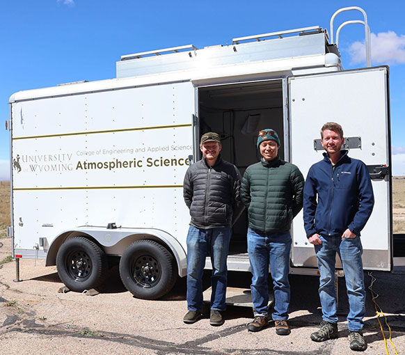 three men standing in front of a trailer