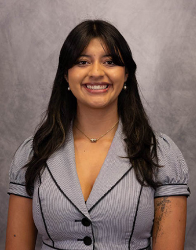 A woman stands in front of a gray background