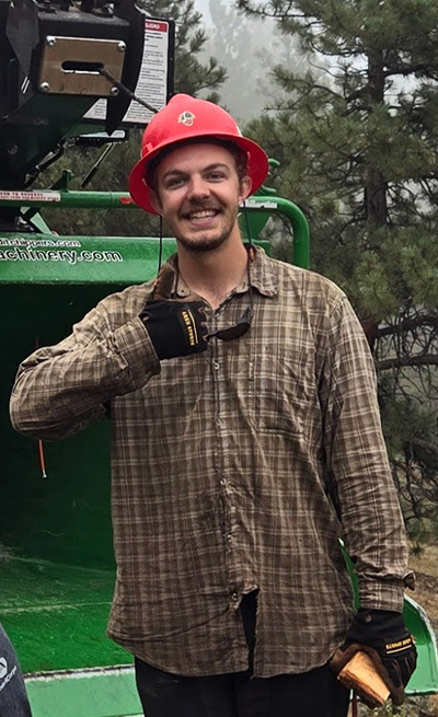 Man stands next to wood chipper