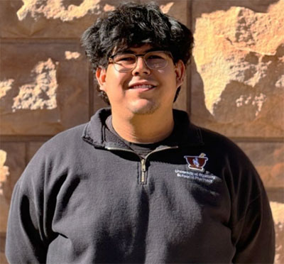 man standing outside in front of a stone brick wall