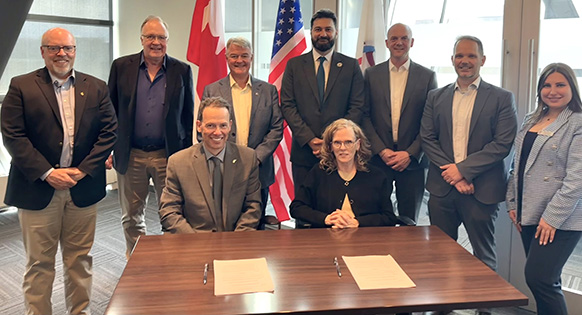 A group of people in a board room pose behind contracts