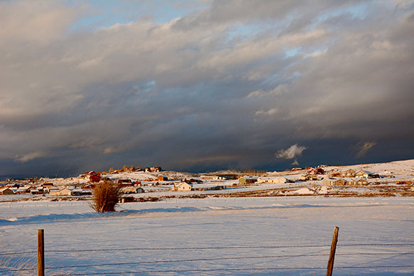 snowy landscape with fields and houses in the distance