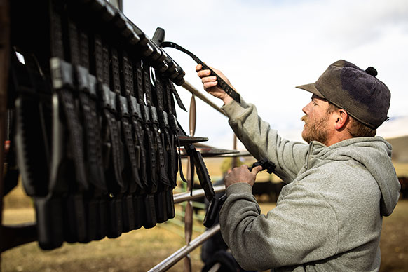 man adjusting large collars on a rack outside