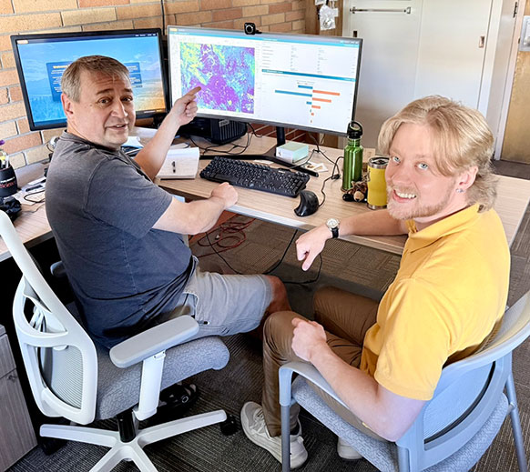 two people at a computer, indicating the screens