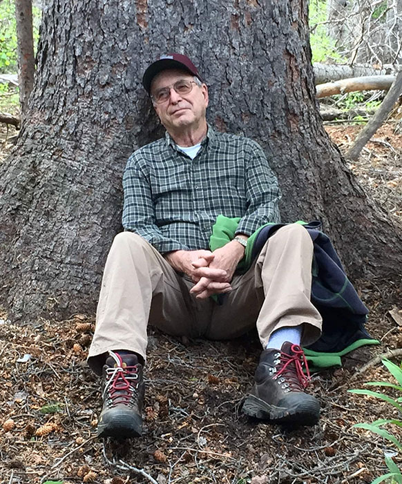 man sitting against a large tree
