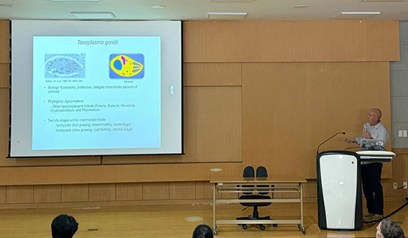 man at a podium with a screen display beside him