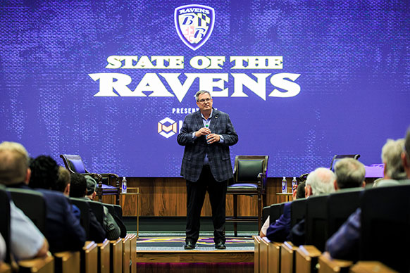 man standing on a raised platform in front of a room full of people