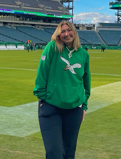 woman in a green sweatshirt standing on a football field