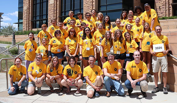 group of people in yellow t-shirts posing on steps