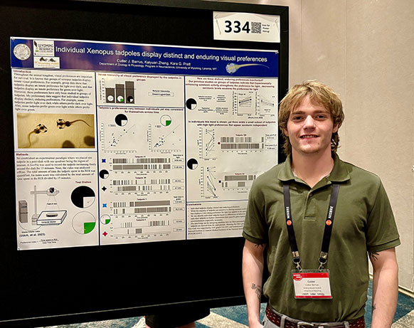man standing beside an elaborate poster mounted on a display board