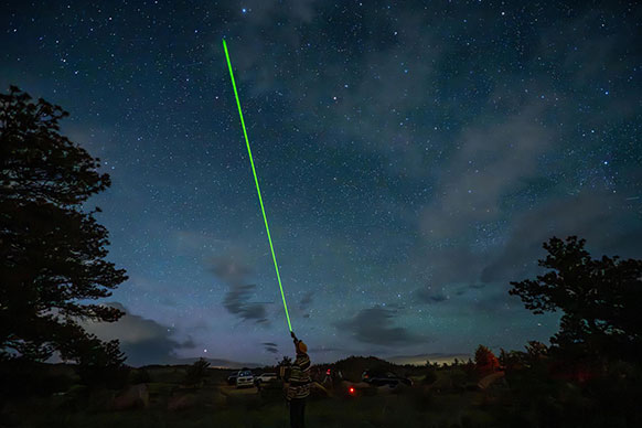 green laser beam going up into the night sky