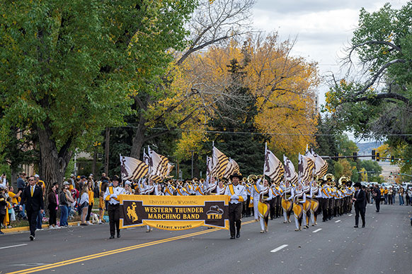 University of Wyoming band marching down an autumn tree-lined street