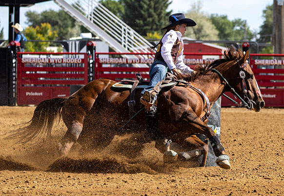 woman riding a horse rounding a barrel