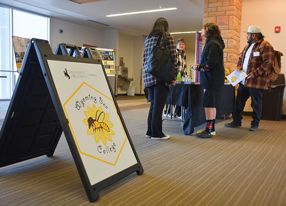 people in a lobby near a sign for the bee college