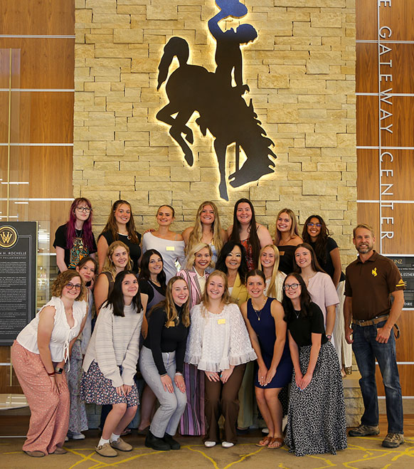 group of people posing under a bucking horse sign on a wall