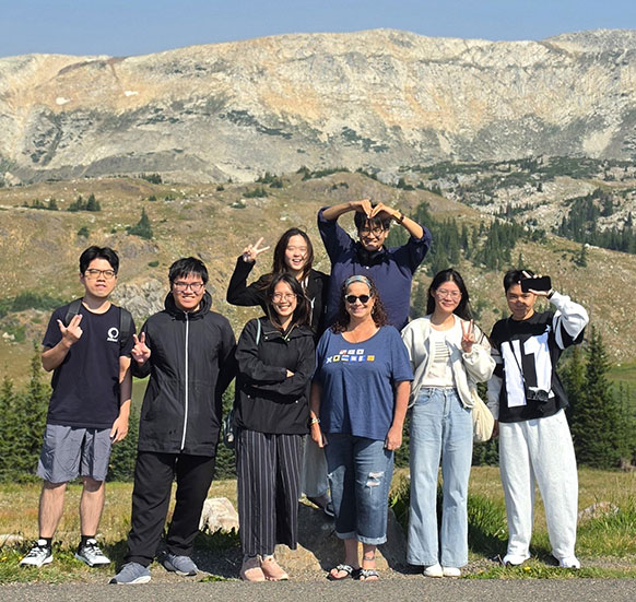 group of people posing in front of mountains