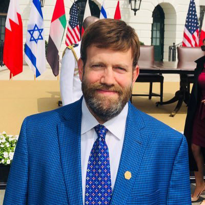 man standing outdoors in front of an array of flags