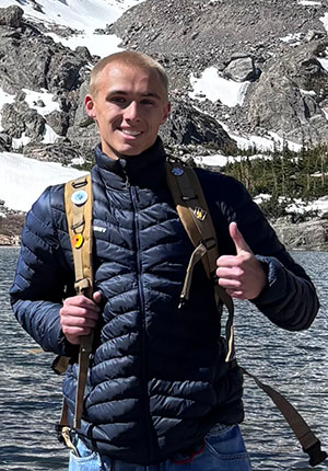 man standing with a lake and mountain in the background