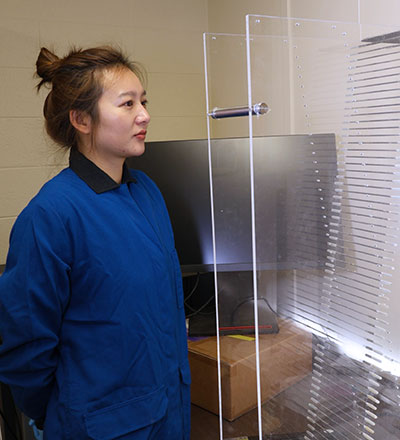 woman standing beside plexiglass panels