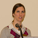 Serious young woman speaking into microphone.