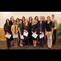 14 students holding papers pose for the camera.