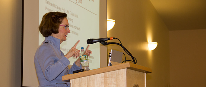 woman speaking and gesturing at lectern