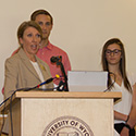 One professor, one male and one female student at podium