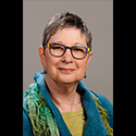 woman with short cropped hair, glasses, and colorful scarf around her collar