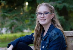 student in a denim jacket sitting outside 