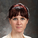 woman with dark brown hair, pulled back with red highlights