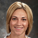 young woman with warm smile, short blond hair with dark roots