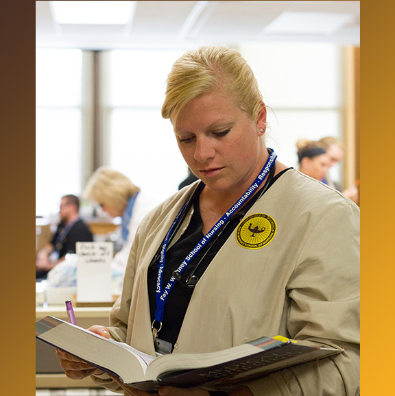 Student refers to textbook prior to starting a new nursing skill