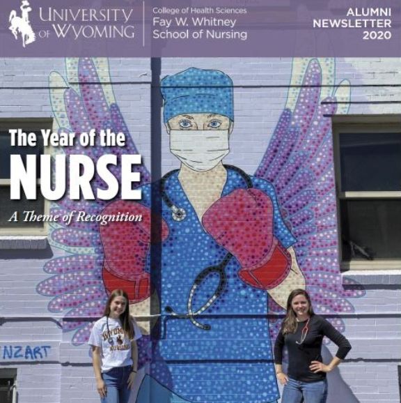 Two students stand next to a nursing mural on a wall