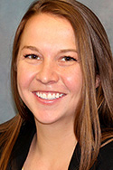 young woman with light brown hair pulled back; yellow jewelry