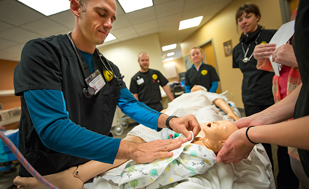 Male student swaddles infant in obstetrics simulation