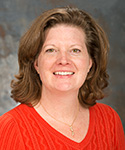 woman with reddish-brown hair and orange sweater