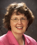 woman with short brown hair in pink suit