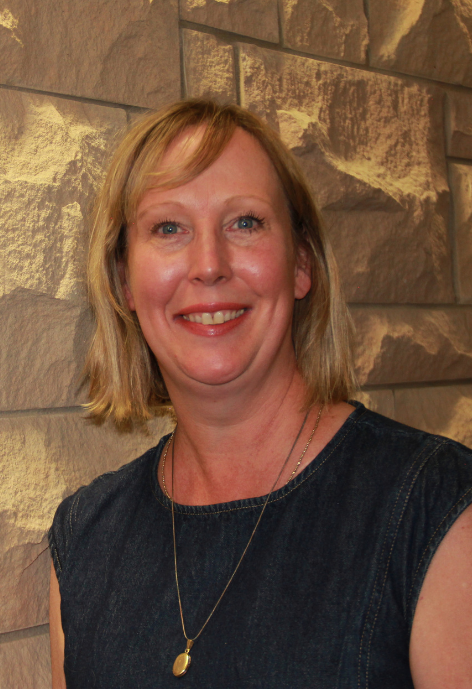 carrie barr in denim top standing in front of lime stone wall