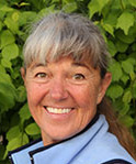 woman with silver bangs standing in front of leafy tree